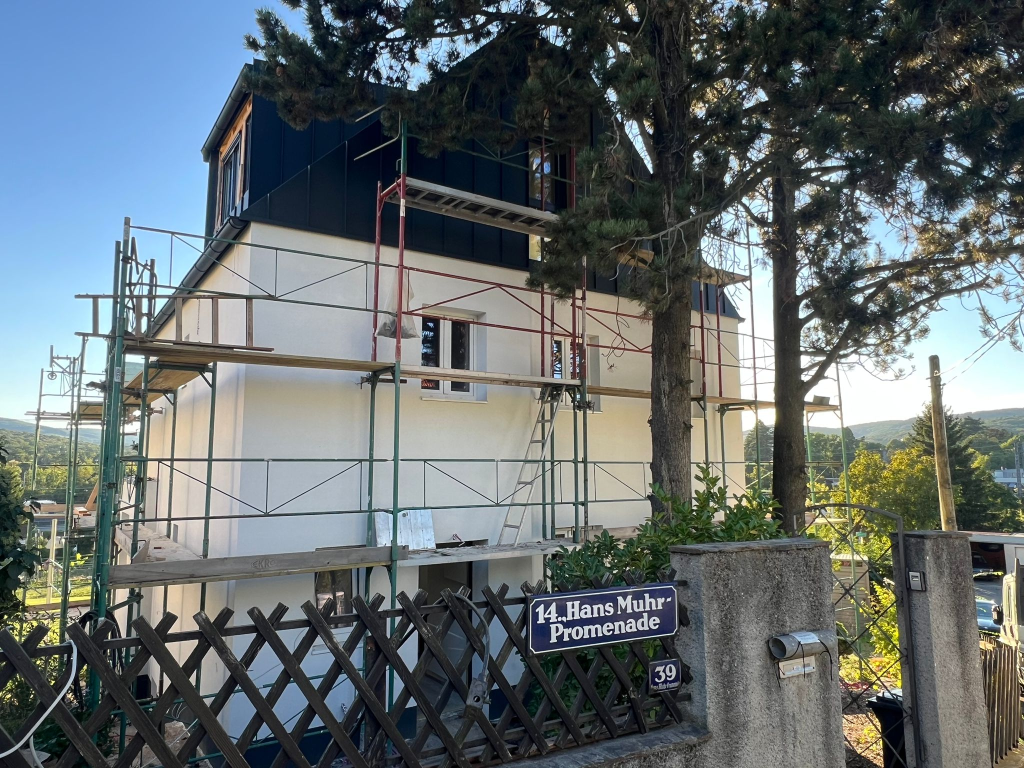 Hausbau Wien 14. Bezirk - Fertige Fassade mit Schwarzblech-Aufstockung und weißem Außenputz